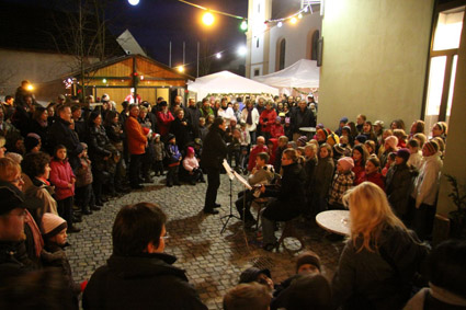 1. Kürnacher Weihnachtsmarkt  Einstimmung in den Advent  Kürnach   Erstmalig verwandelte sich der Kürnacher Kirchberg beim 1. Kürnacher Weihnachtsmarkt in ein Lichtermeer weihnachtlicher Stimmung. In festlich geschmückten Hütten auf dem Kirchberg, auf dem Platz um das neugestaltete Haus der Vereine, wurde verschiedenes Kunsthandwerk und weihnachtliches Gebäck angeboten. Unzählige Besucher erlebten einen stimmungsvollen Weihnachtsmarkt und ließen sich von dem tollen Programm der Kürnacher Vereine  verzaubern. Adventlicher Gesang des Kinder- und Jugendchores und des Gesangvereins, Blasmusik, Kinderkarussell, duftender Glühwein, Getränke, Bratwürste und weihnachtliche Leckereien und das Aroma frisch gebrannter Mandeln hatte eine Vielzahl an Gästen auf den Advent eingestimmt. Bürgermeister Thomas Eberth freute sich über den Zuspruch weit über den Erwartungen und lobte die ehrenamtliche Helferinnen und Helfer: „Wieder grandios, was die Kürnacher Vereine hier gezaubert haben, eine weitere Attraktion im Kürnacher Jahreskreis“. Sowohl die Kinder als auch die Erwachsene zeigten sich begeistert von ihrem 1. Kürnacher Weihnachtsmarkt bei perfektem Wetter. Insofern wunderte es nicht, dass sehr viele über Stunden vergnüglich am Kirchberg verweilten, bis schließlich der Nachtwächter seinen Spruch hören ließ: „Hört, Ihr Leut’, und laßt euch sagen, unsere Glock’ hat zehn geschlagen! Dieser Weihnachtsmarkt ist aus, geht nun all’ geschwind nach Haus.“  Bildunterschrift: 1.Bürgermeister Thomas Eberth eröffnete zusammen mit dem Kinderchor und vielen hundert Gästen den 1. Kürnacher Weihnachtsmarkt auf dem Platz am Haus der Vereine. 