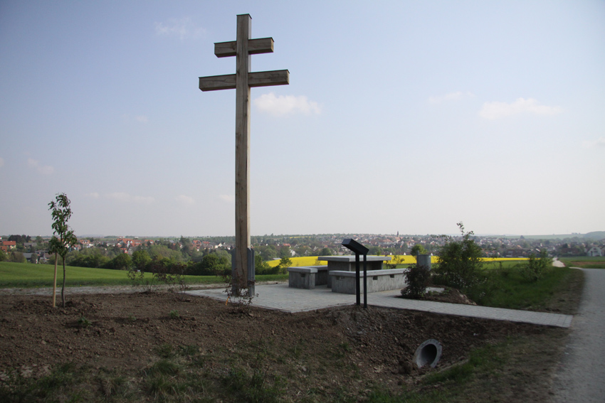 Christine Demel, Rektorin a.D. und Ehrenbürgerin Kürnachs, lässt anlässlich ihres 80. Geburtstages, das ehemalige Doppel- bzw. Patriarchenkreuz von Kürnach wieder errichten.  Ein lang gehegter Wunsch von ihrem Mann Wilhelm Demel, †1984,  in Kürnach ein Holzkreuz aufzustellen, wird somit nun umgesetzt.  1783. Der Geometer, der die drei Flurbücher Kürnachs mit allen Feldern, Wegen und Straßen anlegte, zeichnete auch dieses Doppel- oder auch Patriarchenkreuz, etliche Bildstöcke und die Kreuzigungsgruppe vor der Grießmühle in die Karten ein. Irgendwann hat wohl ein Sturm das Kreuz umgeworfen und es geriet in Vergessenheit. Diese Kreuze, im 9. Jahrhundert von den griechischen Brüdern, Gelehrten und Heiligen Kyrill und Method nach Ungarn gebracht, wurden bald überall in Europa als Schutzzeichen aufgestellt und auf Kirchtürmen und Kirchengebäuden angebracht. Sie dienten den Gläubigen zur Abwehr von allem Übel, das von außen her die Gemeinschaft der Menschen in Dörfern oder Städten bedrohen konnte:  Unwetter, Gewitter, Krankheiten, kriegerische Ereignisse.  „Patriarchenkreuze“ werden sie nach den Patriarchen von Jerusalem genannt, denen ein derartiges Kreuz vorangetragen wurde oder die es als Brustschmuck trugen. Kyrill und Method wurden 1980 durch Papst Johannes Paul II. Schutzpatrone Europas.  Dank gilt schon jetzt folgenden Personen,  die an der Erstellung des Kreuzes beteiligt sind: Meinem Sohn Matthias Demel 1. Bürgermeister Thomas Eberth, Kürnach Forstwirt & Obmann der Feldgeschworenen Reinhard Heinrich, Kürnach Schreiner Bruno Waldherr, Prosselsheim, Sägewerk Statiker Karl Walch, Kürnach Kunstschmied Adolf Röding, Kürnach Zimmermeister Andreas Förster, Estenfeld Bauspenglerei Klaus Göbel, Kürnach Bauunternehmen Werner Pfenning, Kürnach Reinhold Konrad, Autohaus Konrad, Estenfeld Freiwillige Feuerwehr Kürnach